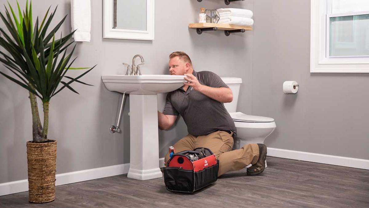 An image of a plumber working on a bathroom sink.