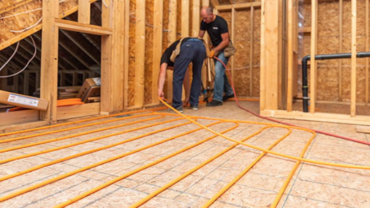 Two individuals installing radiant heating.