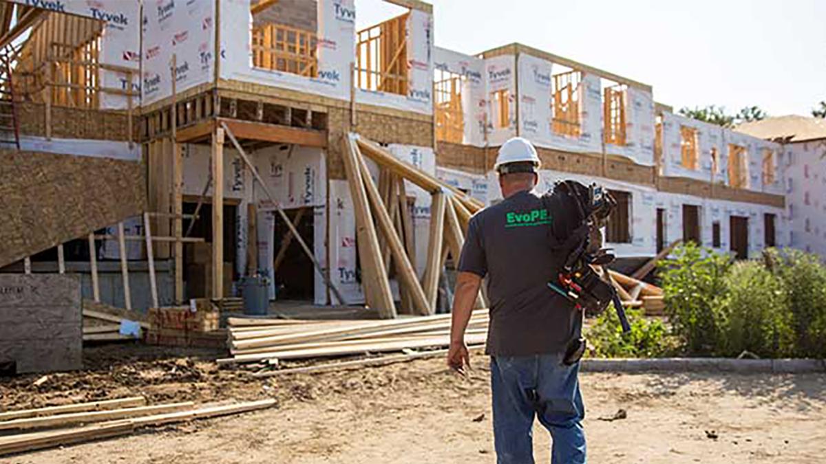 Construction worker installing plumbing components on a job site, highlighting labor shortage challenges in the skilled trades industry.