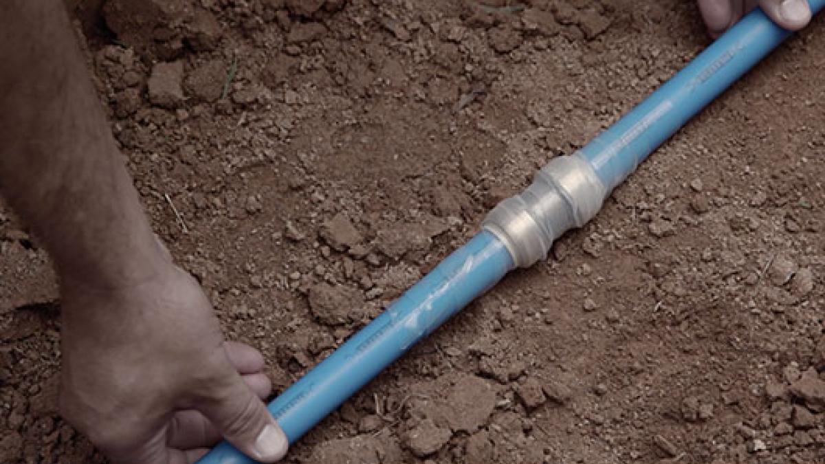 Contractor installing a SharkBite fitting underground with PEX pipe.