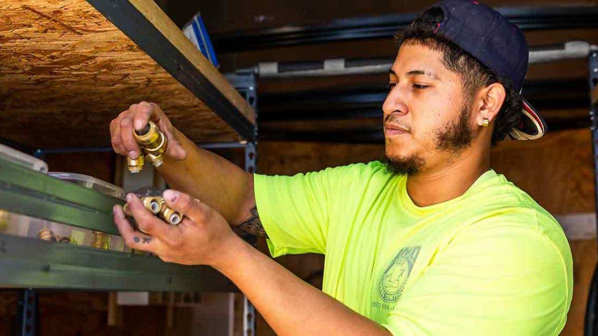 Trade school students learning plumbing skills in a hands-on classroom environment, promoting careers in the skilled trades.