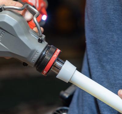 Person using a PEX expansion tool on white PEX pipe.