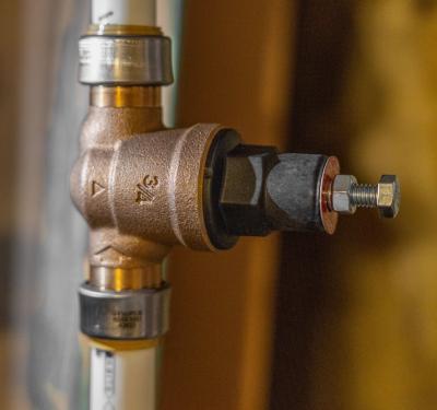 SharkBite pressure reducing valve installed on a water supply line with white PEX tubing.