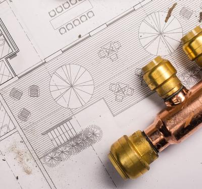 SharkBite brass push-to-connect plumbing manifold system shown on home blueprint design, featuring multiple color-coded outlet branches for individual room water control and simplified whole-house distribution configuration