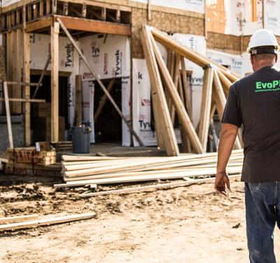 Contractor carrying tools at a new construction job site featuring SharkBite EvoPEX fittings, highlighting efficient plumbing installation in residential builds.
