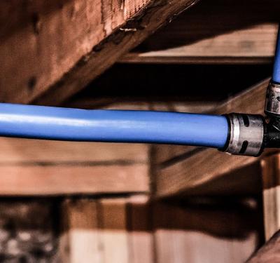 close-up of hands connecting an evopex tee to blue PEX pipe.