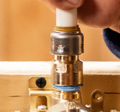 A plumber installing a SharkBite Max fitting