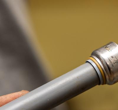 A SharkBite Max push-to-connect coupling transitioning between two different types of pipe 