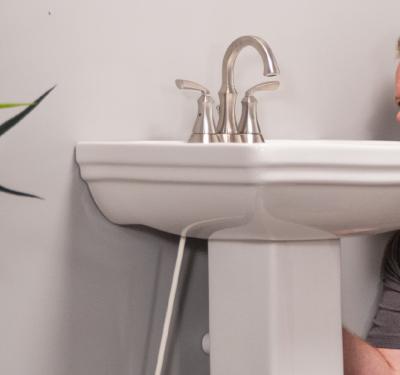 A plumber installing a pedestal sink