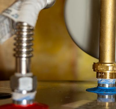 The top of a water heater with a SharkBite Max corrugated water heater connector installed.
