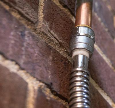 SharkBite brass push-to-connect water heater connector installed on hot and cold supply lines, featuring flexible design for quick, tool-free installation and thermal expansion protection