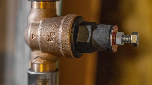 SharkBite pressure reducing valve installed on a water supply line with white PEX tubing.