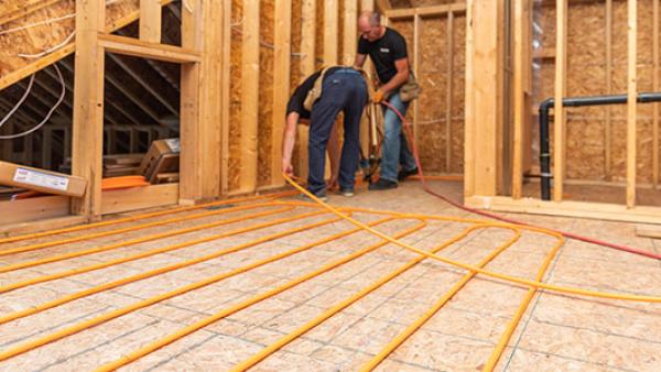 Two individuals installing radiant heating.