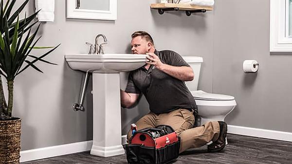 plumber working on a bathroom sink.