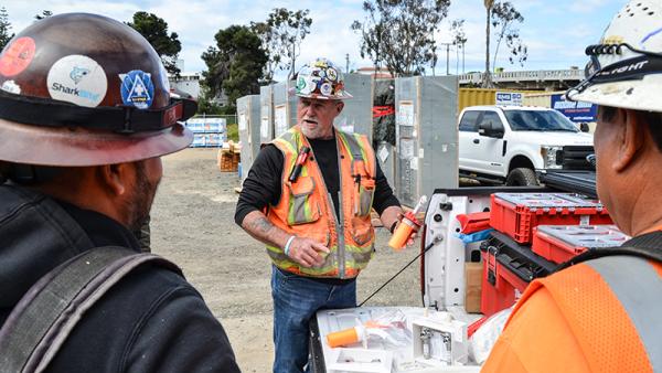 Three plumbers discussing SharkBite products