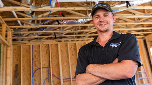 A plumber posing with SharkBite products installed in the background