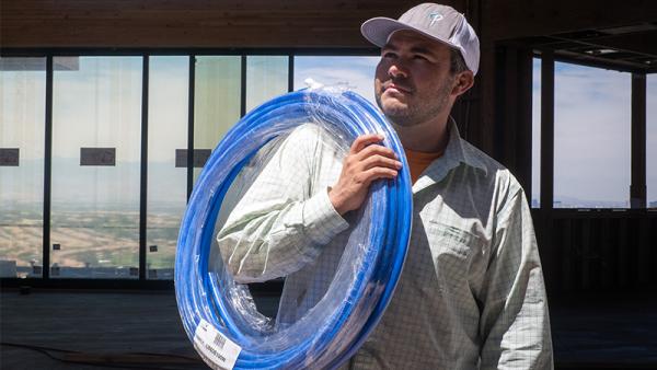 A plumber carrying a coil of blue SharkBite PEX Pipe