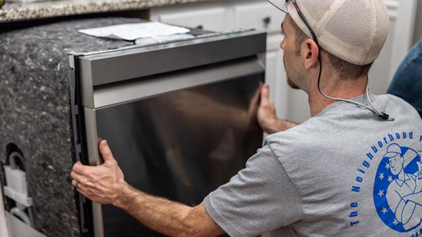 A plumber installing a new dishwasher