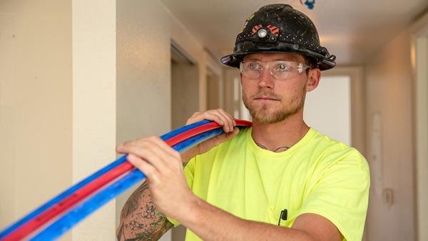 A plumber carrying SharkBite PEX pipe