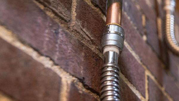 SharkBite brass push-to-connect water heater connector installed on hot and cold supply lines, featuring flexible design for quick, tool-free installation and thermal expansion protection