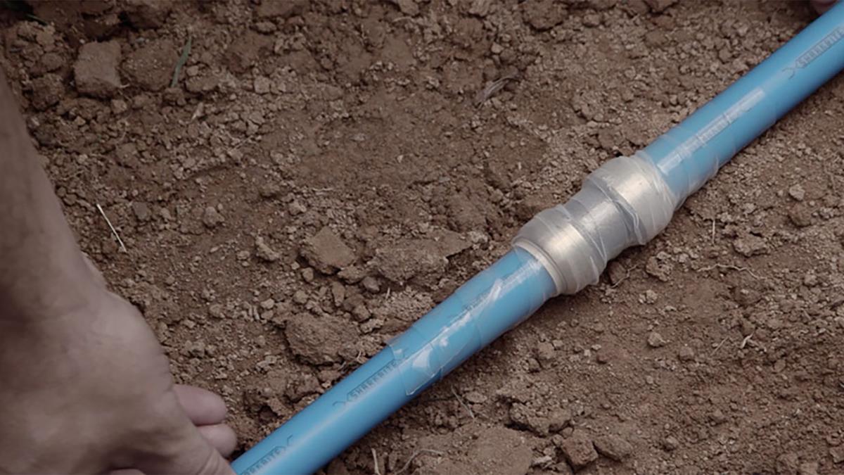 Contractor installing a SharkBite fitting underground with PEX pipe.