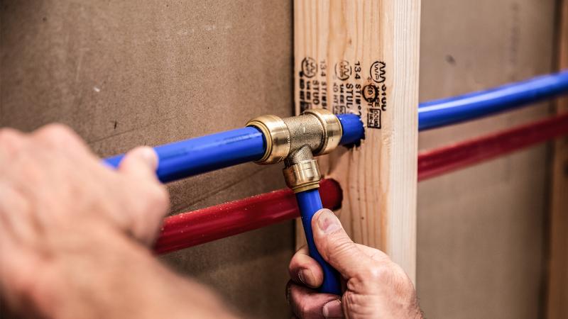 Installing blue PEX pipe on a SharkBite  push-to-connect tee fitting.