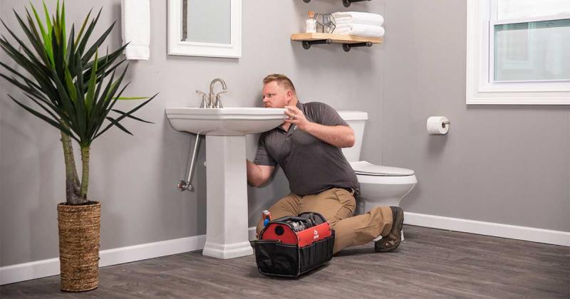 An image of a plumber working on a bathroom sink.