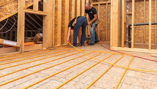 Two individuals installing radiant heating.