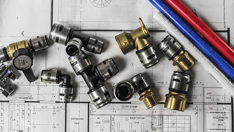 A variety of Evopex fittings and pex pipes laid on a blueprint.