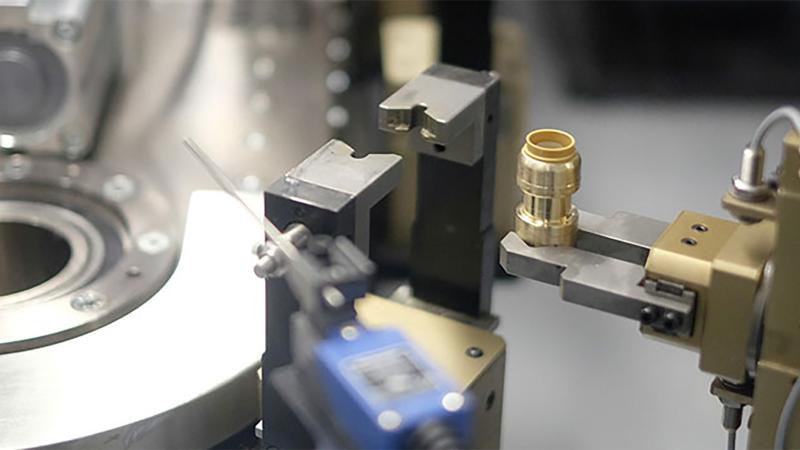 Close-up of a SharkBite fitting being held by a manufacturing machine 