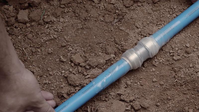 Contractor installing a SharkBite fitting underground with PEX pipe.