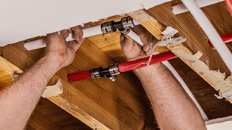 Close up of hands installing EvoPEX  fittings on PEX pipe.
