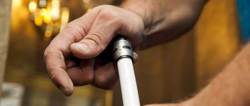 Close-up of hands connecting an EvoPEX fitting with a white PEX pipe.