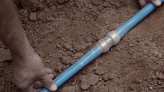 Contractor installing a SharkBite fitting underground with PEX pipe.