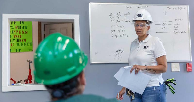 Female plumbing instructor teaching apprentice 