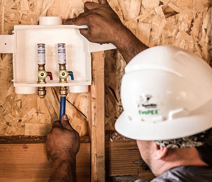 Man in hard hat installing a SharkBite washing machine outlet box 
