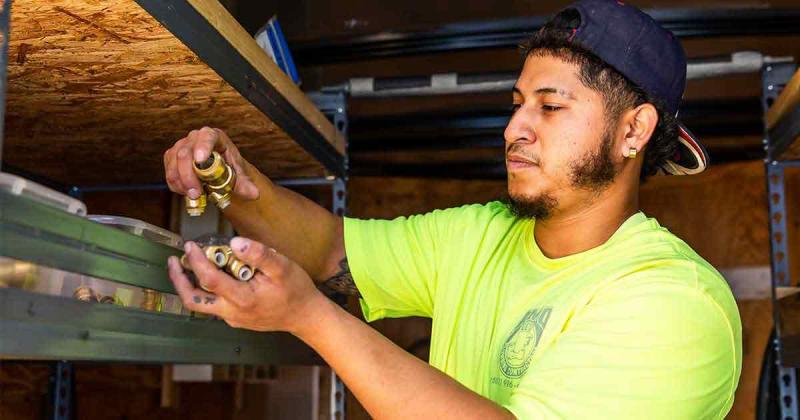 Trade school students learning plumbing skills in a hands-on classroom environment, promoting careers in the skilled trades.